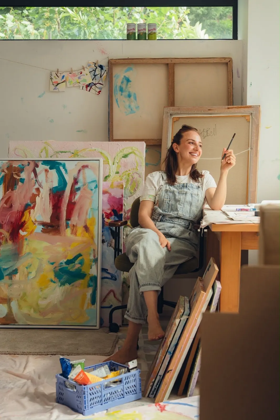 Georgie Bell in her studio, surrounded by large abstract paintings, holding a brush